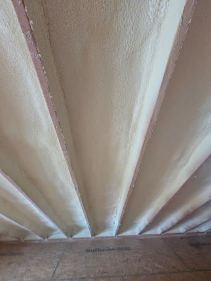 Looking up a sloped ceiling with spray foam filling the bays between the rafters