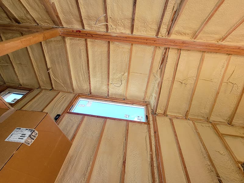 Spray foam on a wall and the roofline around a window in an unfinished room