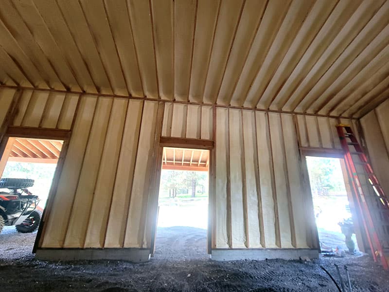 Shop wall with spray foam between the girts around three open door openings