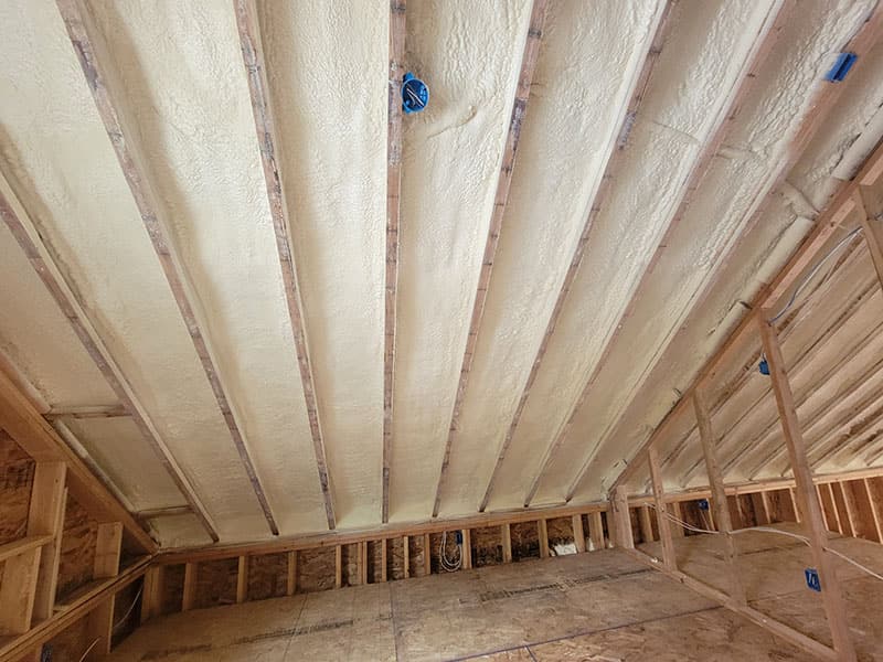Sloped ceiling with spray foam between every rafter and framed walls below