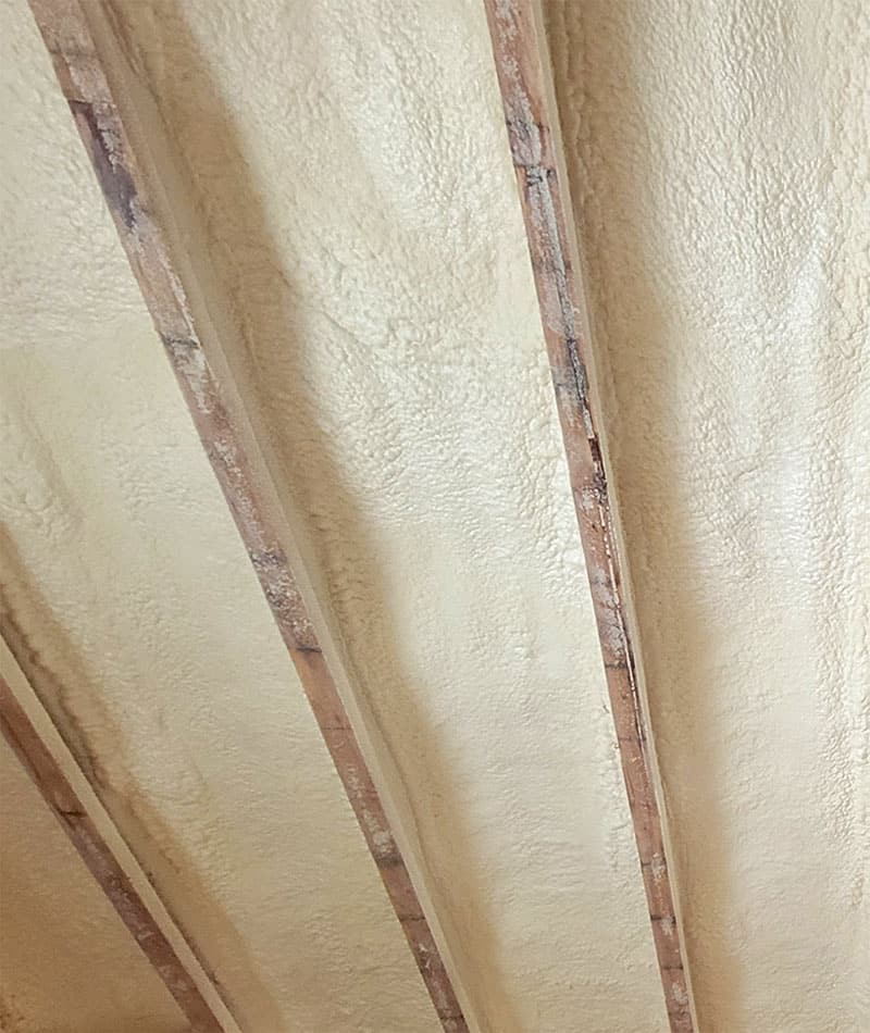 Close-up of smooth spray foam filling the cavities between wood studs