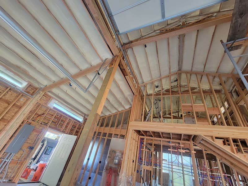 Vaulted framing with spray foam on the ceiling and exterior walls, work lights on stands