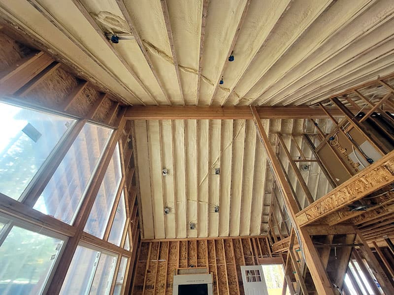 Tall wall of windows with spray foam on the surrounding walls and the ceiling above